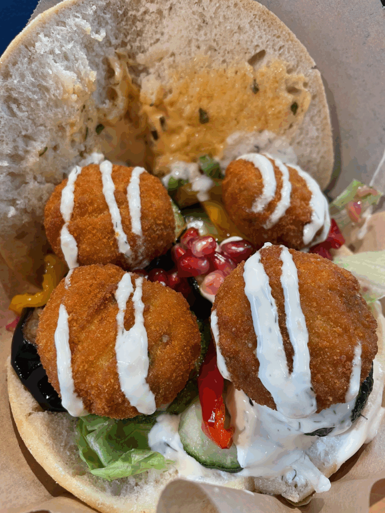 a "falafel" sandwich on pita bread with tzatziki sauce and veggies 