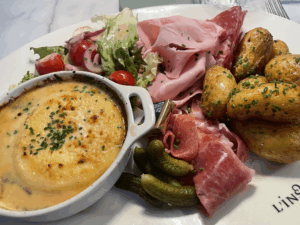 a delicious dinner of cheese, meat, potatoes and cornichons