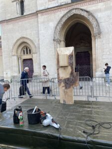 a block of wood sitting on a platform in front of a church, waiting to be carved into