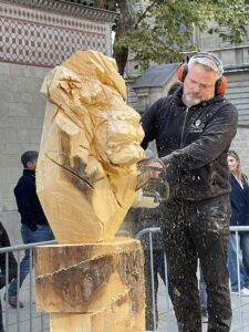 a man carves a lion into wood with a chainsaw