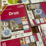 Textbooks for various subjects, including "Droit," arranged on a table. The covers feature images of buildings and logos related to educational programs.