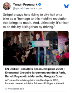 A blue sky screenshot: A group of people celebrates as Grégoire stands in front of a sign, discussing his bike ride to city hall as part of a mobility initiative. The scene captures a moment of enthusiasm and community engagement related to local elections.