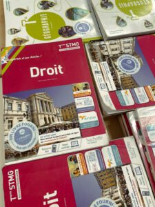 Textbooks for various subjects, including "Droit," arranged on a table. The covers feature images of buildings and logos related to educational programs.