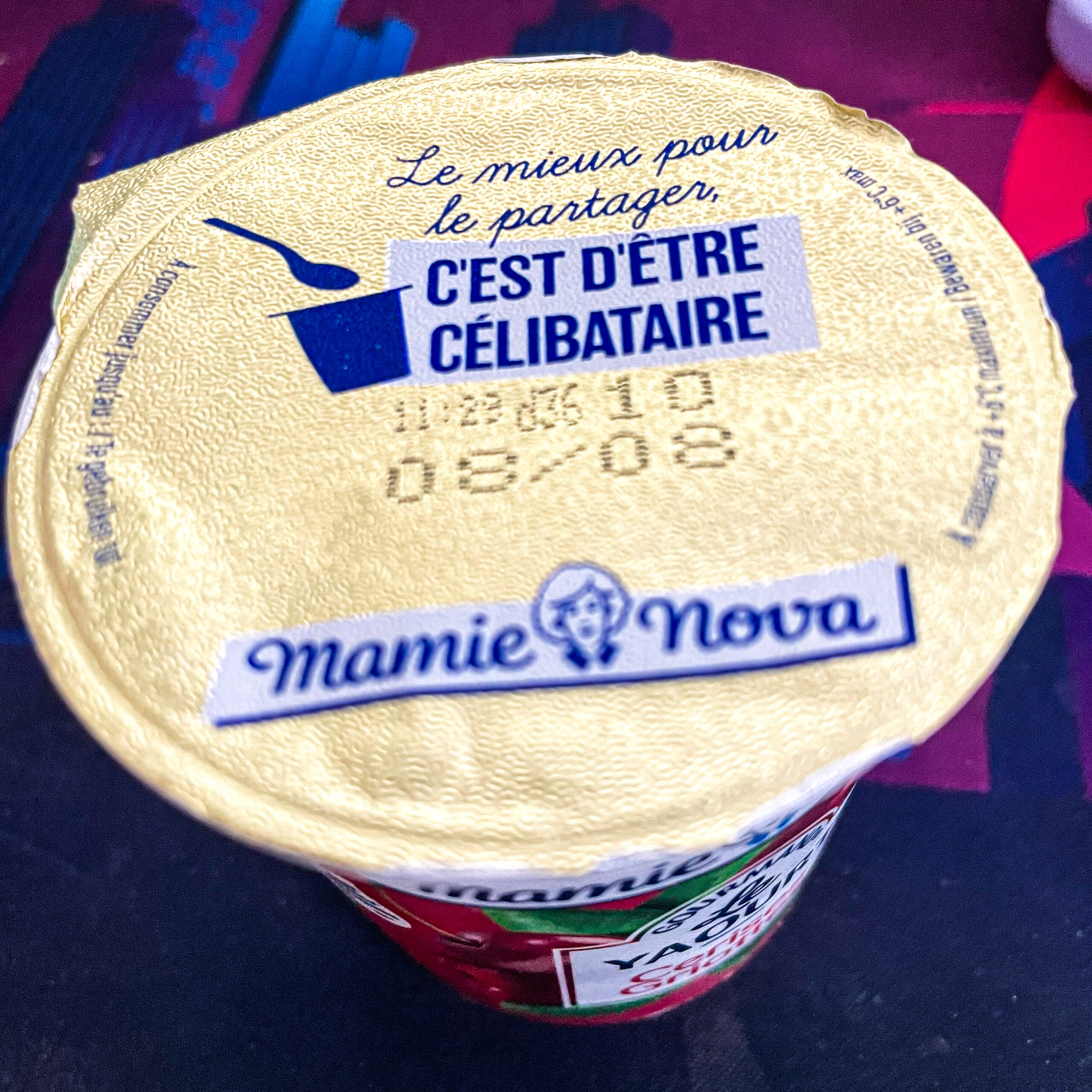 Gold foil lid of a yogurt container with French text that reads "Le mieux pour partager C'est d'être célibataire" and the brand name "Mamie Nova."